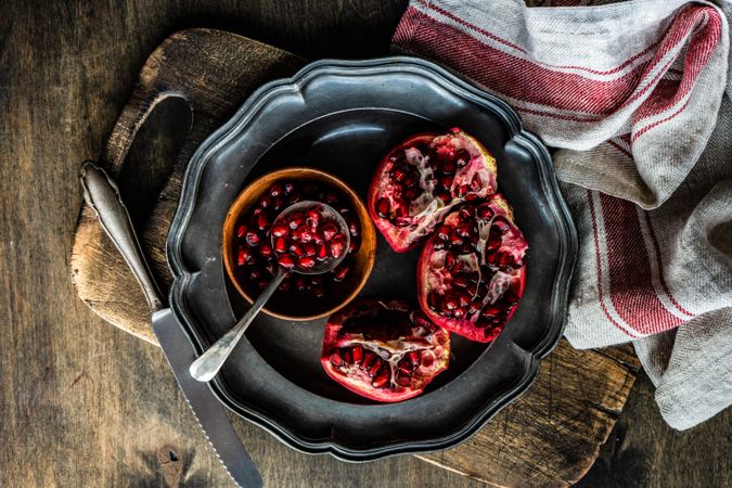 Fresh cut pomegranate on dark bowl with dishtowel