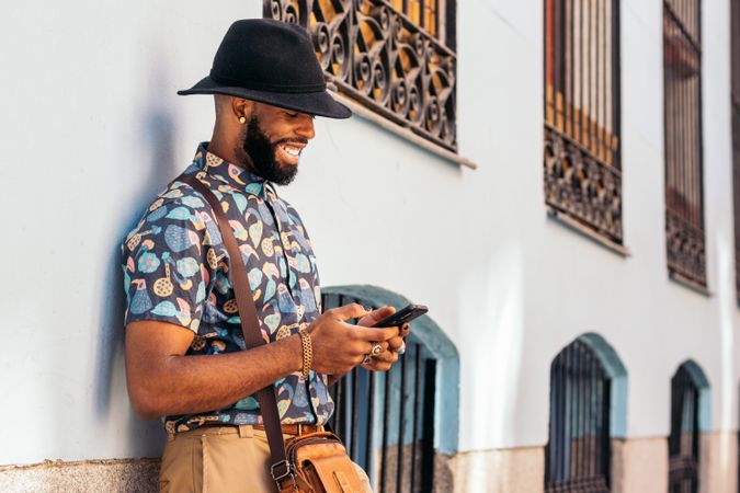 Stylish Black man using smartphone outdoors in the city