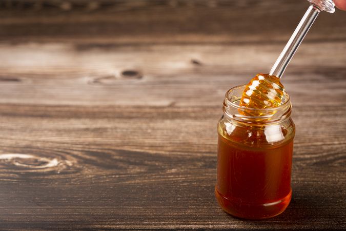 Honey in glass jar on the table.