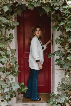 Stylish woman standing near red door