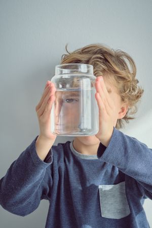 Kid covering face with jar of water