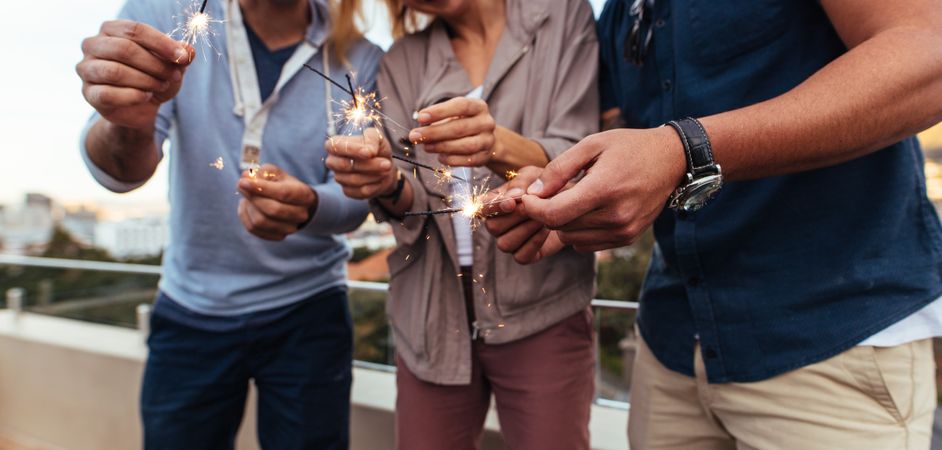 Friends holding sparklers on rooftop party