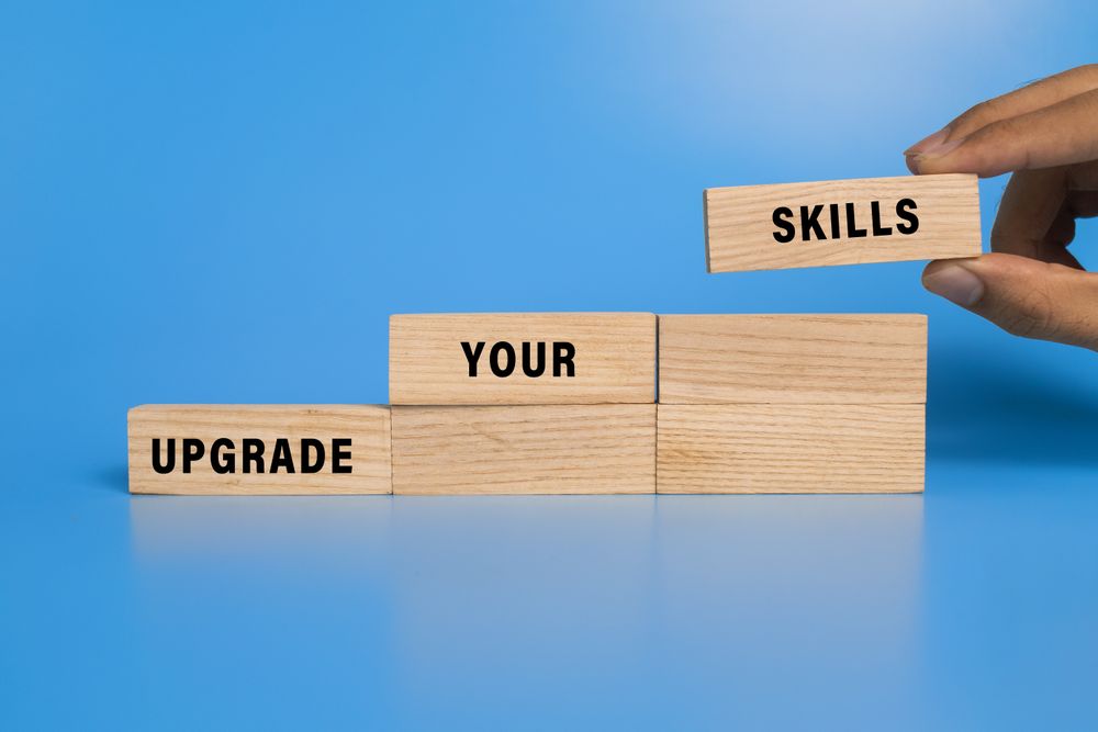 male hand put wooden blocks with upgrade your skills words isolated on blue background