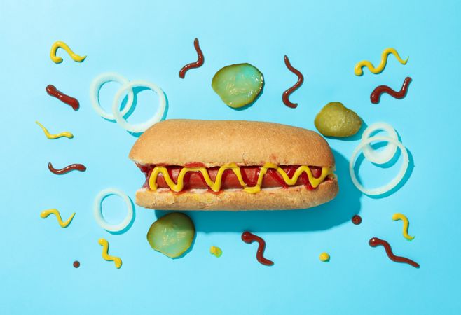 Tasty hot dog and ingredients on blue background