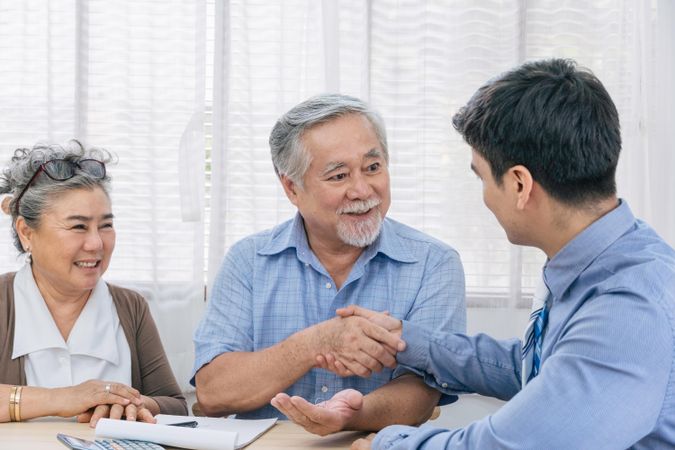 Older Asian couple making deal to purchase real estate