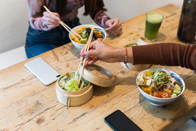 Crop woman eating poke dish in restaurant