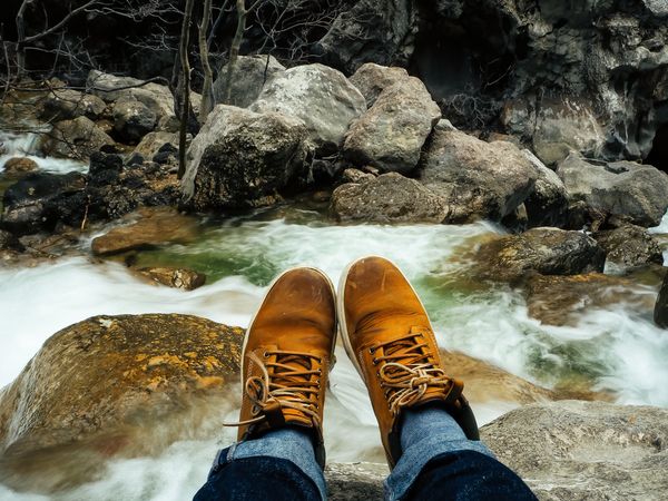 Sitting on top of the rock of the river with rocks and forest in soft-focus in the background of Plitvice Lakes National Park, Croatia.