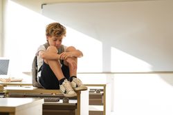 Schoolkid sitting on table in classroom