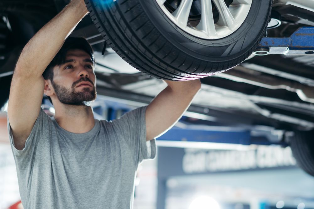 Auto worker checking under car in repair shop