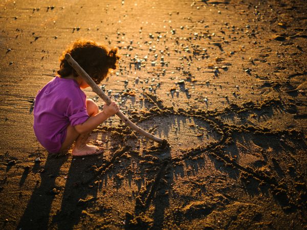 Cute little girl playing with sand at beach