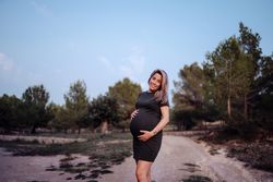 Charming pregnant woman standing on walkway in park