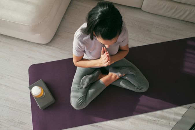 Woman meditating on mat with beer