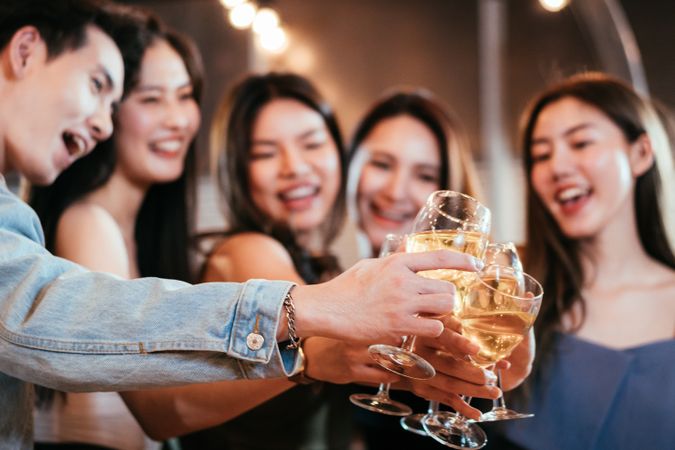 Group of Asian friends smiling and toasting glass of wine together