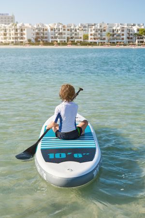 Anonymous boy floating on paddleboard in ocean