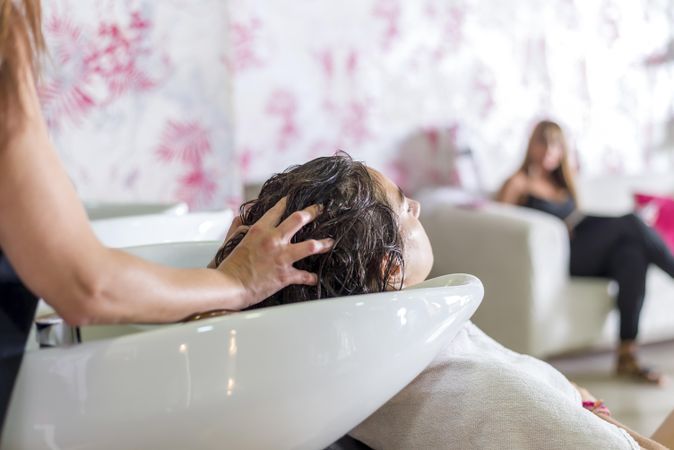 Woman having her hair shampooed in sink at salon