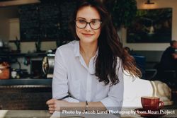 Portrait of attractive female sitting at cafe with notebook and cup of coffee on table 5oBGm0