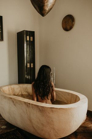 Woman sitting and washing in bath
