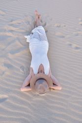 Woman in white dress relaxing on sand