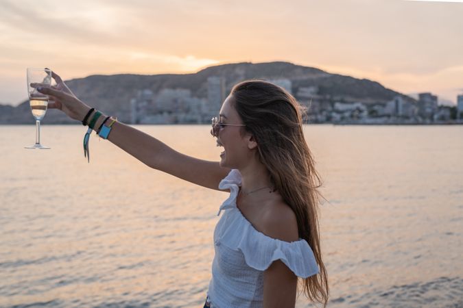 Young woman enjoying wine near sea