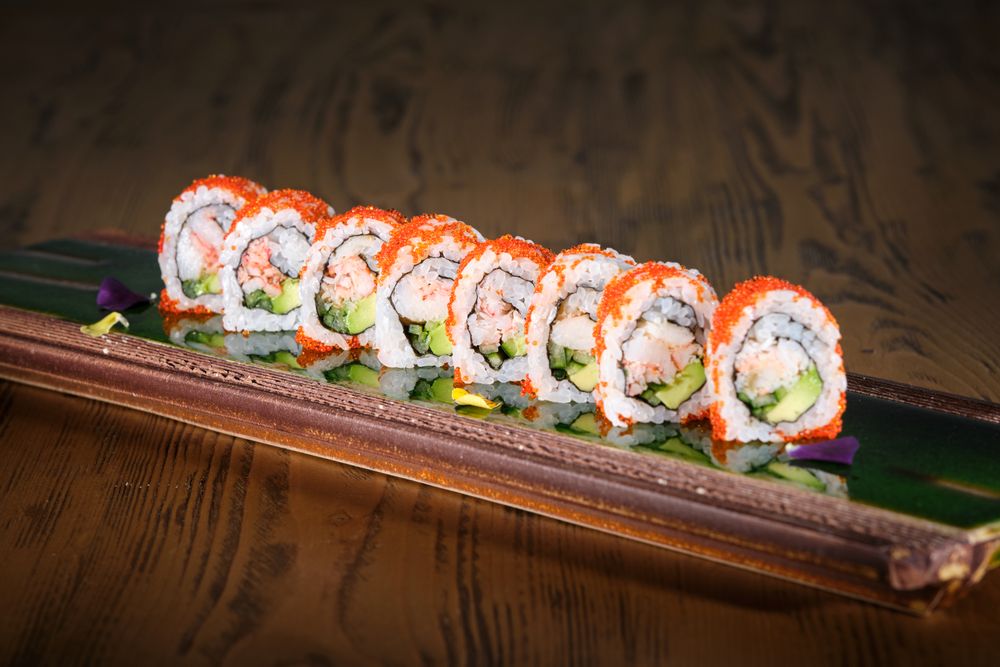 Sushi rolls on serving plank with reflective surface