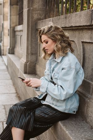 Woman using smartphone near park fence