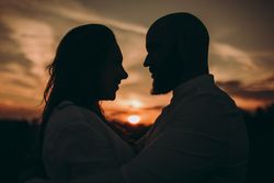 Loving couple embracing while standing against sunset sky