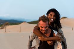 Couple doing piggyback having fun at beach
