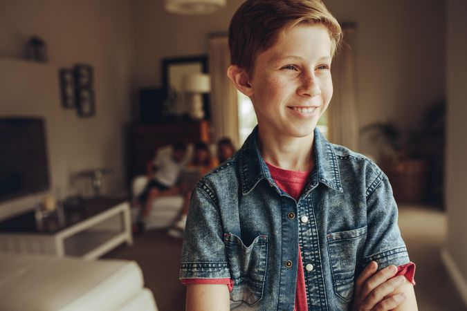 Portrait of a smiling boy standing at home with arms crossed