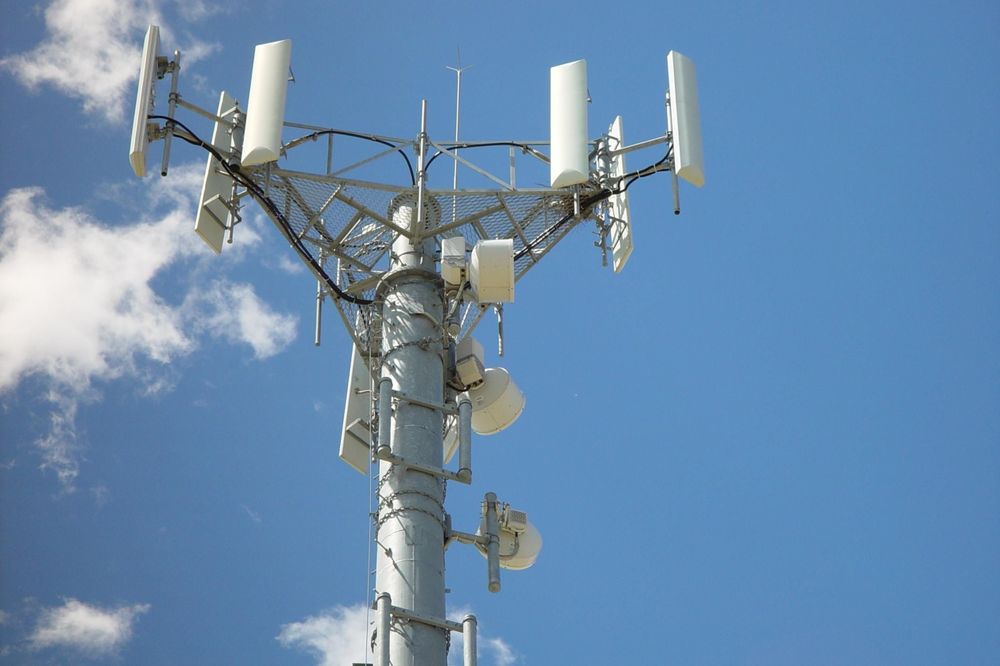 Modern Cell Tower Against a Clear Blue Sky and White Clouds