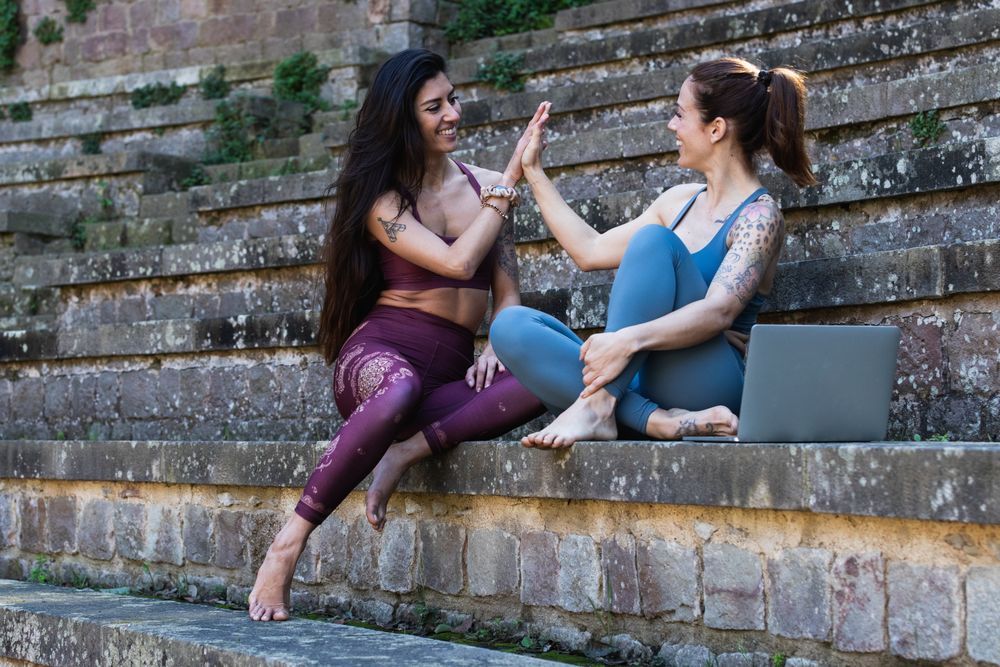 Content multiethnic women giving high five to each other before yoga lesson
