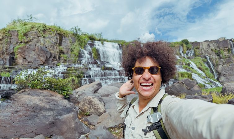 exultant traveler takes selfie with waterfall in the background