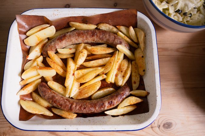 A dish with baked sausages and potatoes, fresh salad