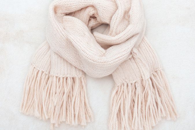 Cream knitted scarf with tassels on marble