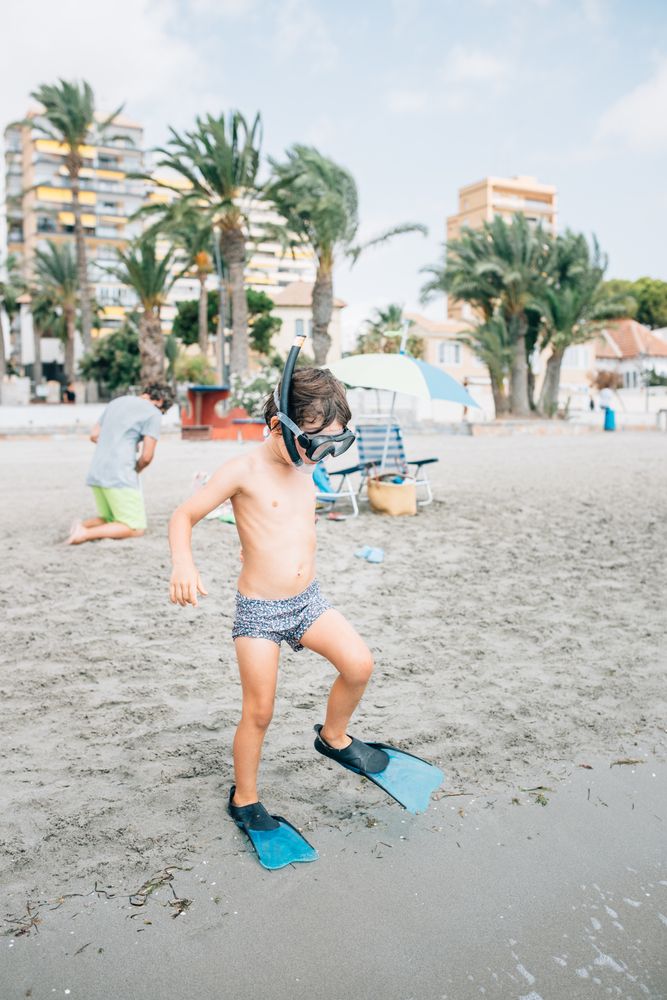 Boy in snorkeling mask and flippers on beach