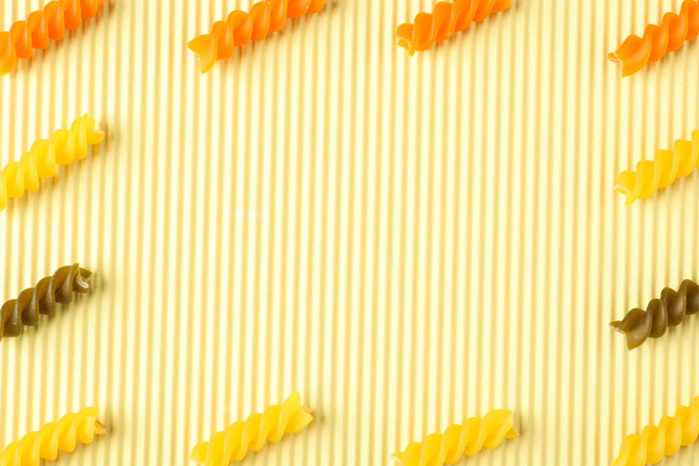 Flat lay composition with color pasta on light background, space for text and closeup