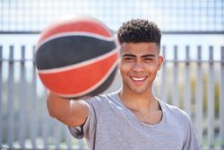 Smiling man standing with ball and looking at camera