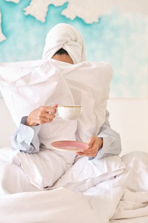 Anonymous female drinking hot coffee on bed