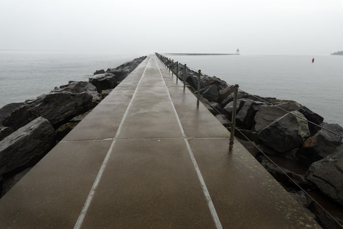 Pier atop boulders leading out to a lighthouse in Two Harbors, Minnesota