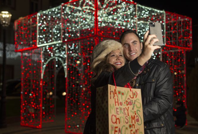Happy couple standing and taking selfie on smartphone in night