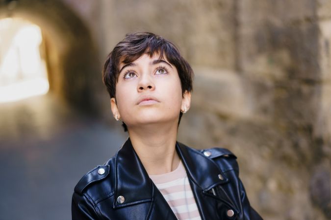A Contemplative Young Woman Dressed in a Stylish Leather Jacket Deeply Looking Upwards