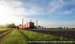 Red train traveling in a summer landscape 49V7Lb