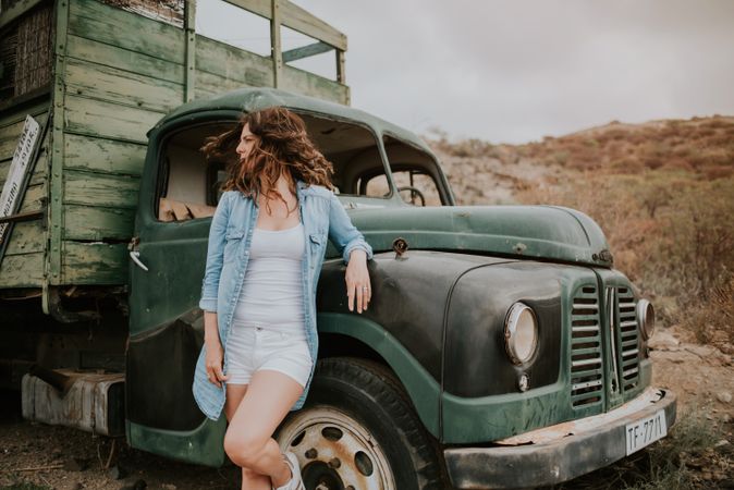 Relaxed female leaning on old truck
