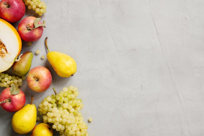 Apple, pear, melon, grapes on grey background