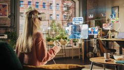 Woman Sitting in Loft Living Room at Home, Using Virtual Reality Headset with Controllers to Check Social Media Streaming App