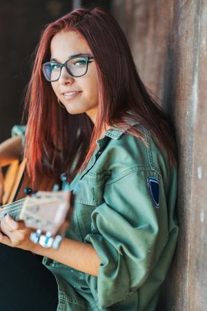 Romantic woman playing guitar leaning on wall
