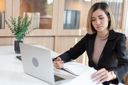 Woman taking notes in front of her laptop