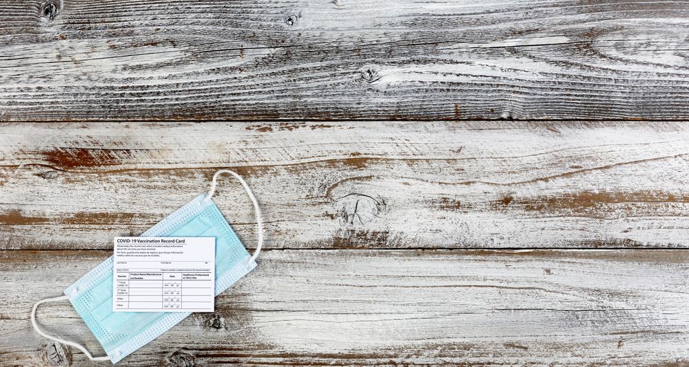 Covid 19 vaccination record card with facemask on desktop