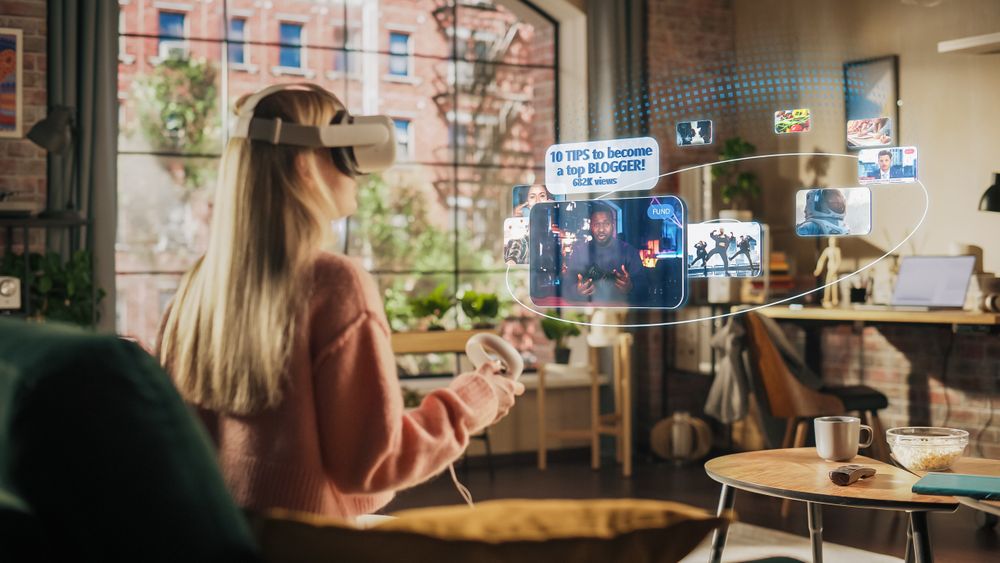 Woman Sitting in Loft Living Room at Home, Using Virtual Reality Headset with Controllers to Check Social Media Streaming App