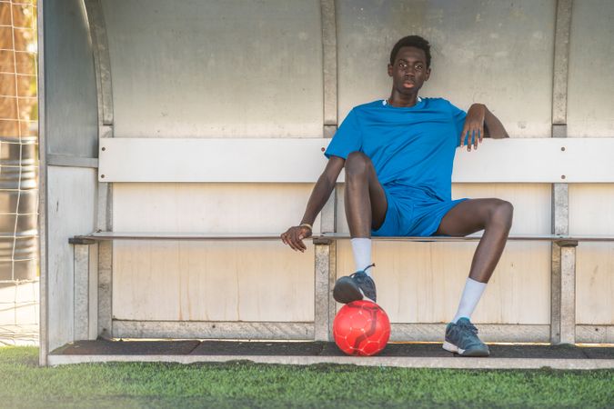 Black football player resting on bench