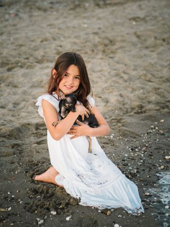 Girl with little dog on sandy beach